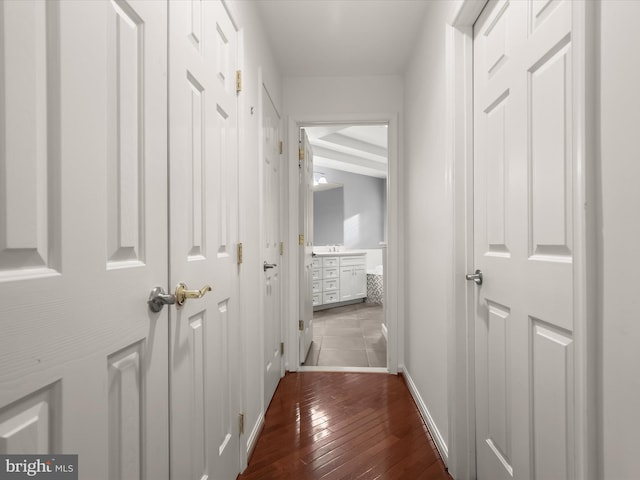 hallway featuring dark wood-style flooring and baseboards