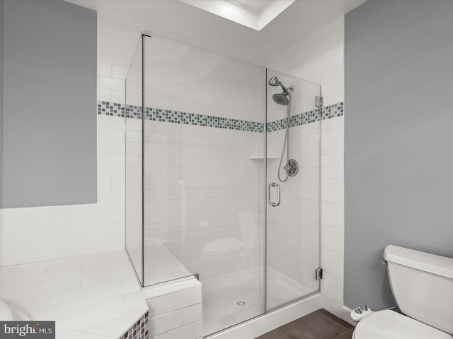 bathroom featuring toilet, a stall shower, and tile patterned flooring