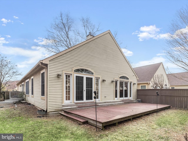 back of house featuring french doors, a yard, a chimney, fence, and a wooden deck