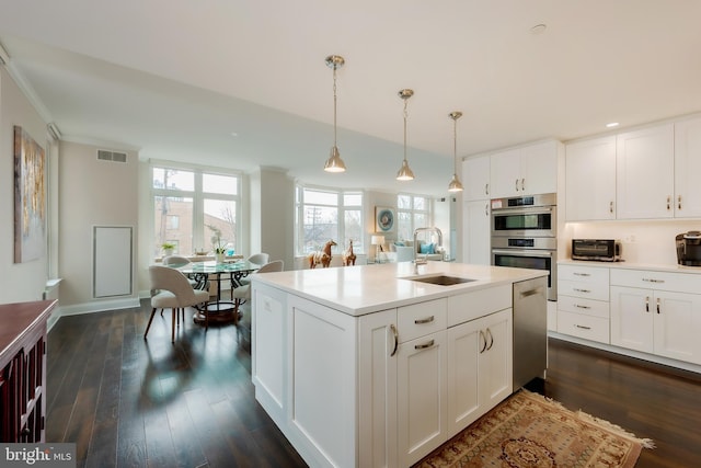 kitchen featuring decorative light fixtures, stainless steel appliances, white cabinets, and sink