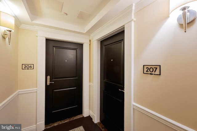 entryway with ornamental molding and a raised ceiling