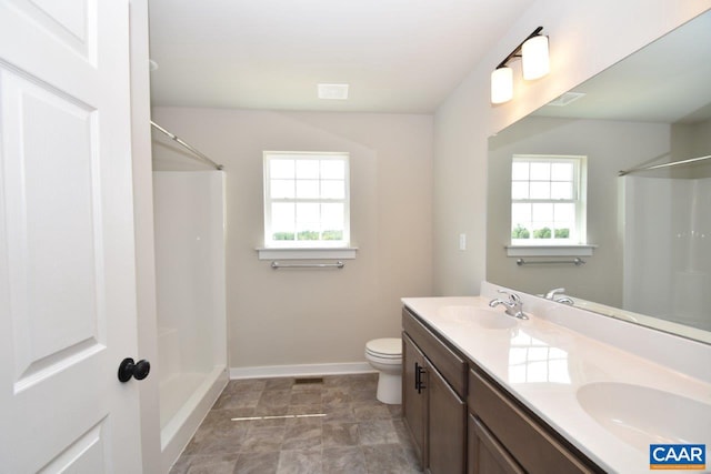 bathroom featuring toilet, vanity, a wealth of natural light, and walk in shower