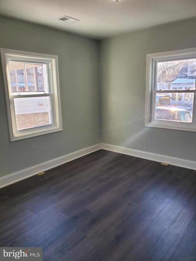 empty room with plenty of natural light and dark hardwood / wood-style floors