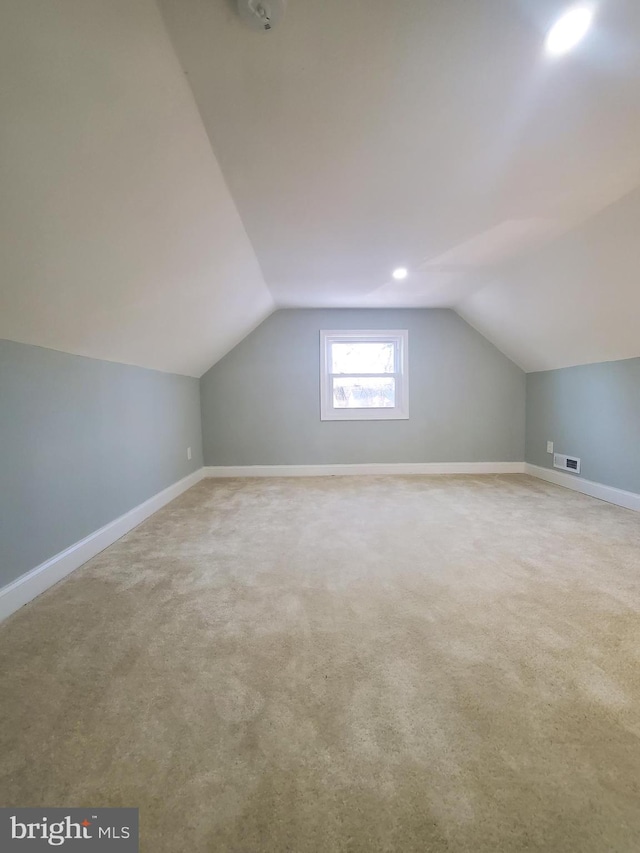 additional living space with vaulted ceiling and carpet floors