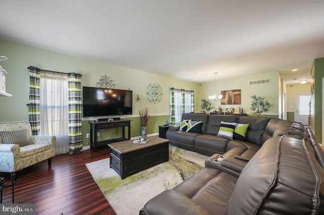 living room with plenty of natural light, dark hardwood / wood-style floors, and a notable chandelier