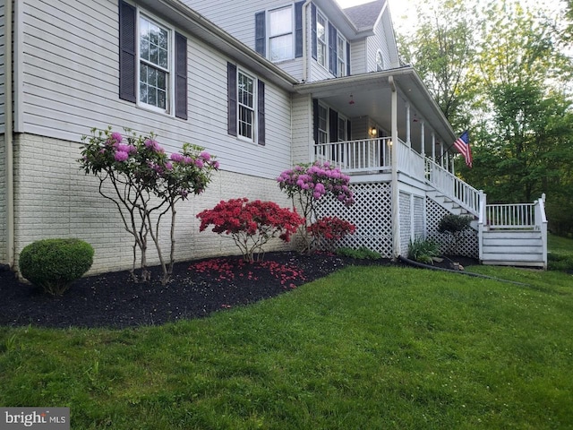 view of side of property featuring a porch and a lawn