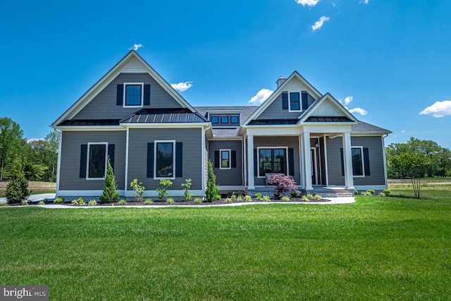 view of front facade with a standing seam roof, covered porch, metal roof, and a front lawn