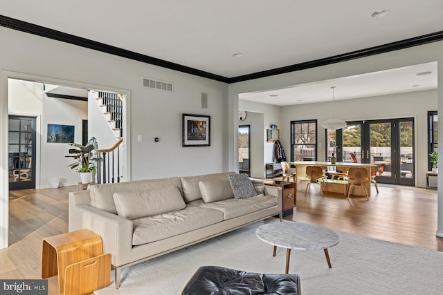 living room featuring light wood-type flooring, french doors, and ornamental molding