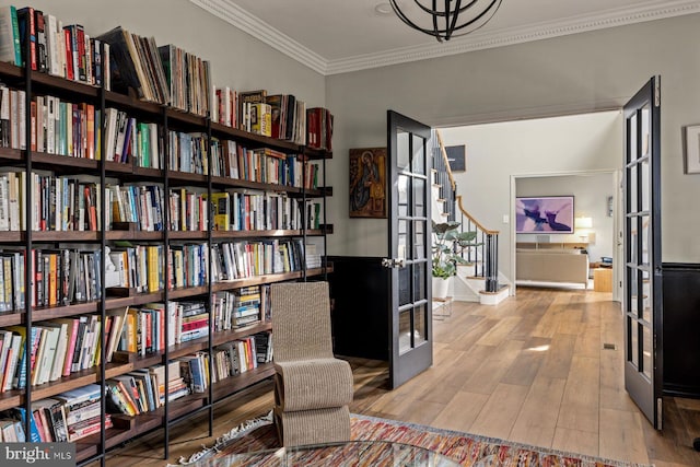 living area featuring light wood-type flooring, french doors, and crown molding