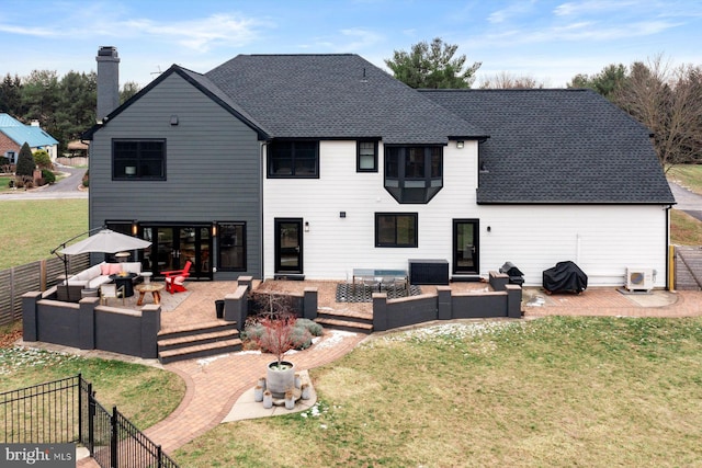 rear view of property featuring a patio area, a lawn, and an outdoor living space with a fire pit