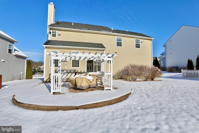 snow covered back of property featuring a pergola