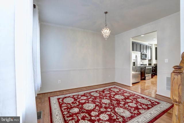 unfurnished room with an inviting chandelier, crown molding, and light hardwood / wood-style floors