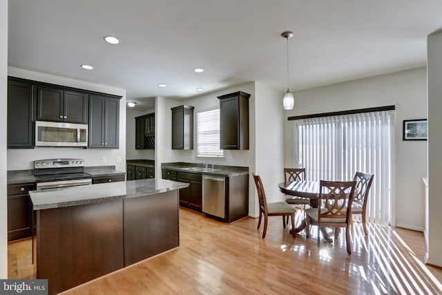 kitchen with pendant lighting, dark brown cabinetry, stainless steel appliances, and a kitchen island