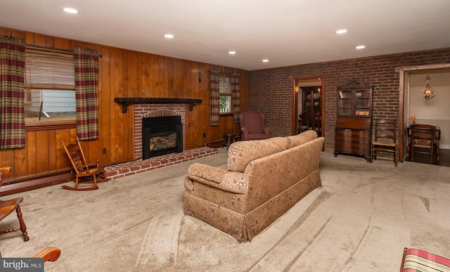 living room featuring a fireplace, light colored carpet, wood walls, and brick wall