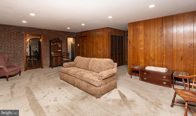 carpeted living room featuring wooden walls and brick wall