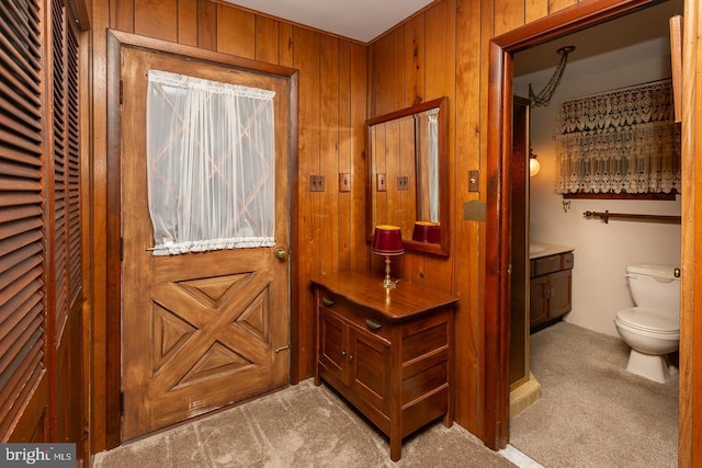 doorway to outside featuring light colored carpet and wooden walls