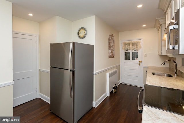 kitchen with dark hardwood / wood-style flooring, sink, radiator heating unit, and appliances with stainless steel finishes