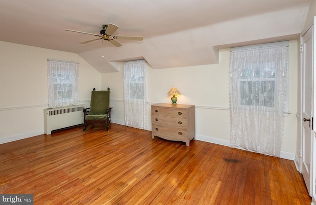 unfurnished room with ceiling fan, radiator, vaulted ceiling, and light hardwood / wood-style flooring