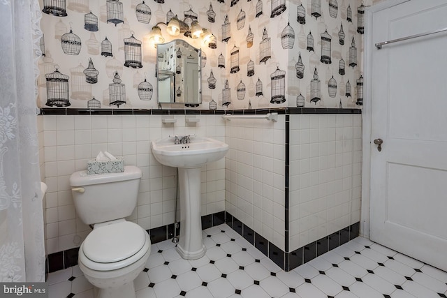 bathroom with sink, tile walls, and toilet