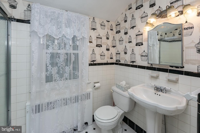 bathroom featuring radiator, tile walls, and toilet