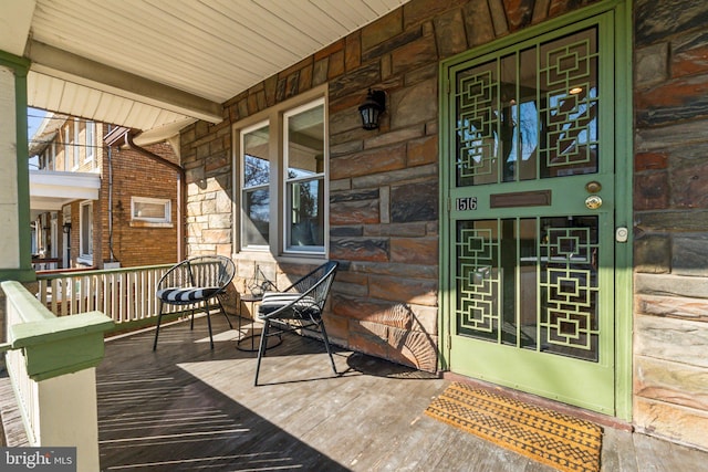 entrance to property featuring a porch and stone siding