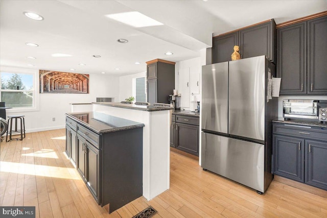 kitchen with light wood-type flooring, a center island, and stainless steel refrigerator