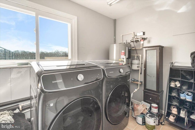 washroom with electric water heater, tile patterned floors, and washer and dryer