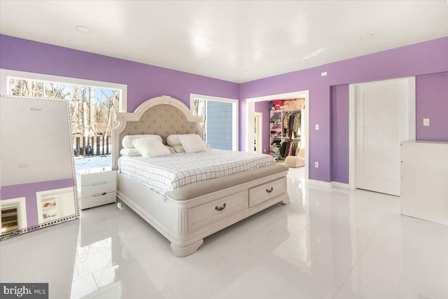 tiled bedroom featuring a walk in closet and a closet