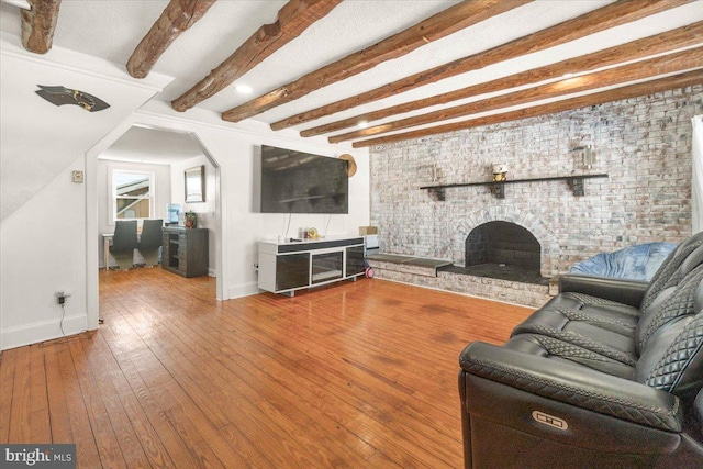 unfurnished living room with a brick fireplace, wood-type flooring, and beamed ceiling