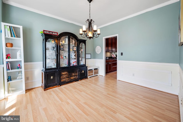 interior space with ornamental molding, an inviting chandelier, and light hardwood / wood-style flooring