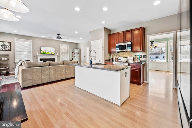 kitchen with a kitchen island with sink, sink, light hardwood / wood-style floors, and range