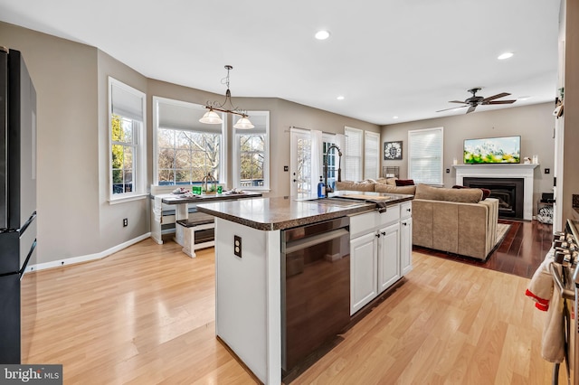 kitchen featuring sink, a center island, white cabinets, decorative light fixtures, and light wood-type flooring