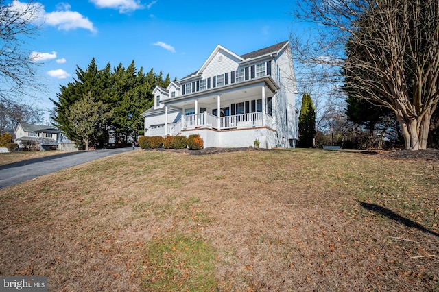 front facade featuring covered porch and a front yard