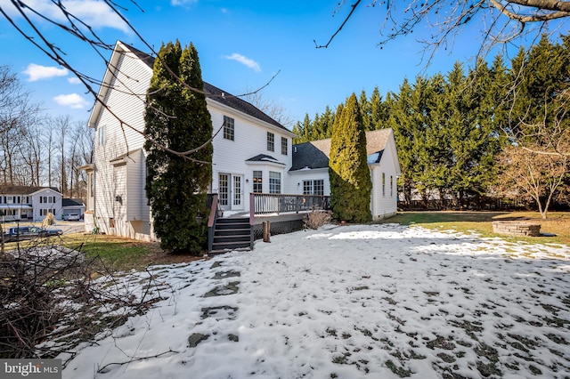 snow covered back of property with a wooden deck