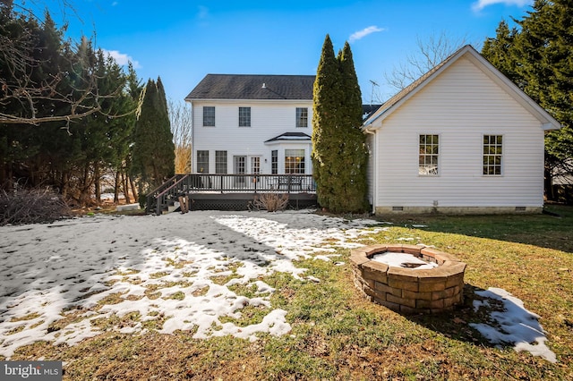 rear view of property featuring a yard, a deck, and a fire pit