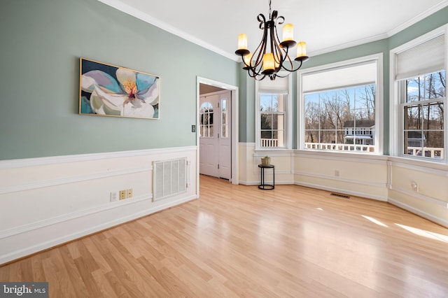 unfurnished dining area with crown molding, a chandelier, and light wood-type flooring