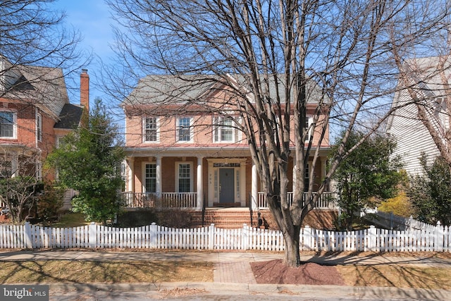 view of front facade with a fenced front yard, a porch, and brick siding