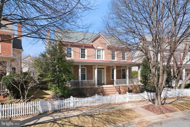 view of front facade with a fenced front yard, brick siding, and a porch