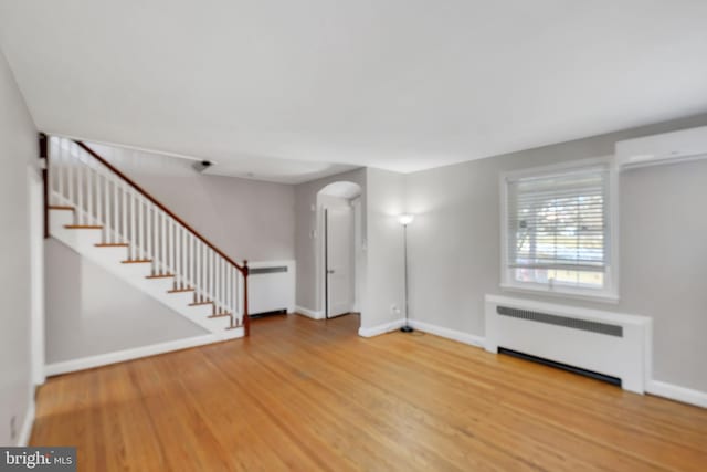 unfurnished living room featuring radiator heating unit and wood-type flooring