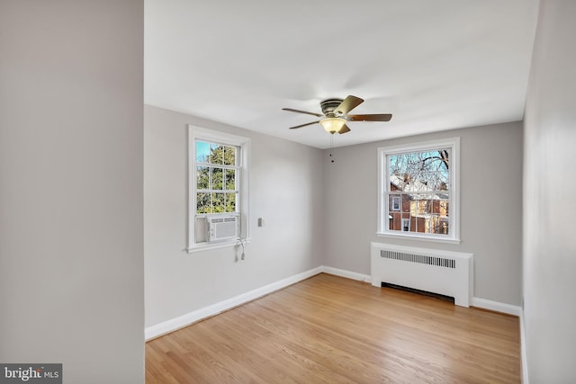 unfurnished room featuring ceiling fan, radiator, light hardwood / wood-style flooring, and a wealth of natural light