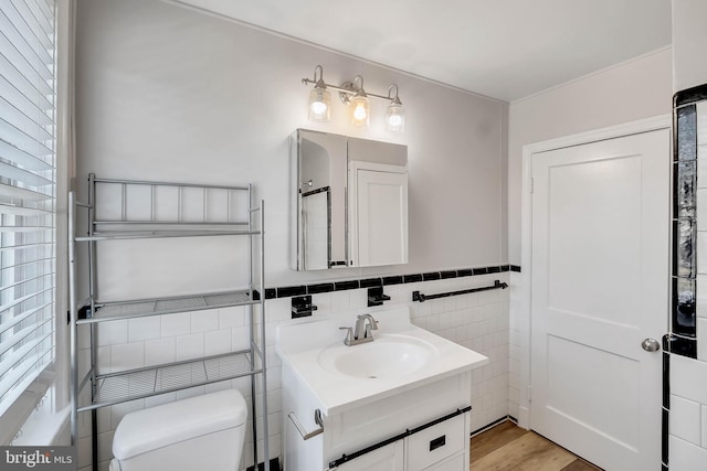 bathroom with tile walls, vanity, wood-type flooring, and toilet