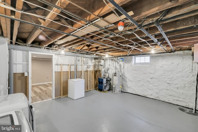 basement featuring water heater, fridge, and washer and clothes dryer