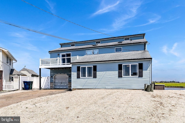 rear view of property with a garage and a balcony