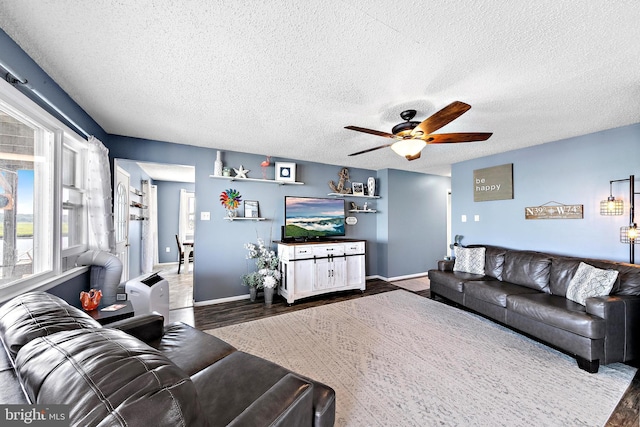 living room with ceiling fan, dark wood-type flooring, and a textured ceiling