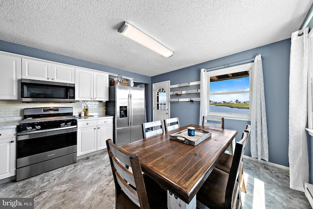 kitchen featuring decorative backsplash, white cabinets, a textured ceiling, and appliances with stainless steel finishes