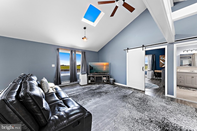 living room featuring ceiling fan, a barn door, a skylight, and high vaulted ceiling