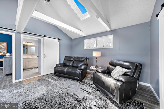 living room featuring a textured ceiling, vaulted ceiling with skylight, a barn door, and dark hardwood / wood-style flooring