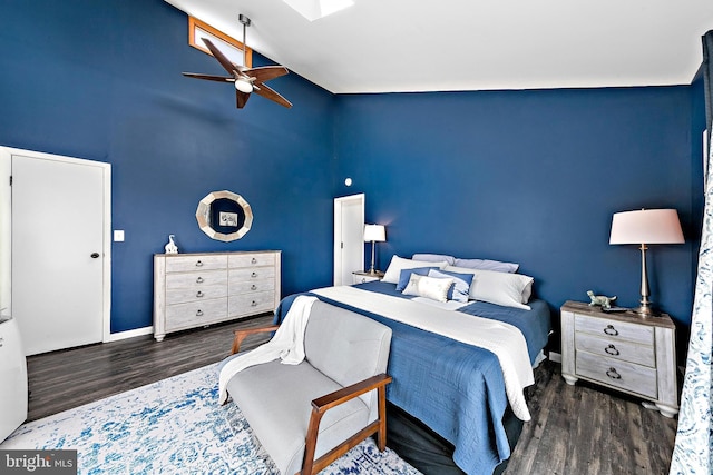 bedroom featuring ceiling fan, dark wood-type flooring, and lofted ceiling with skylight