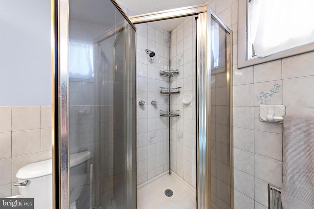 bathroom featuring walk in shower, tile walls, and toilet