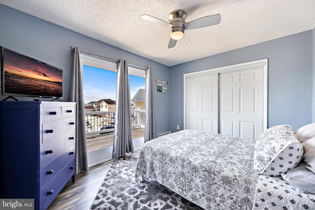 bedroom with a textured ceiling, ceiling fan, a closet, and wood-type flooring